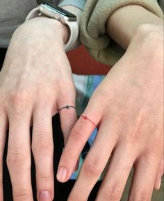 two people with rings on their fingers and one has a small cross on the middle finger