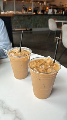 two iced drinks sitting on top of a white table