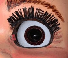 a doll's eye with long lashes and fake eyelashes on the bottom part of it