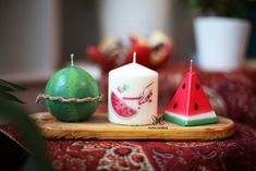 three watermelon candles sitting on top of a wooden tray