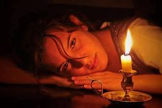 a woman laying down next to a candle