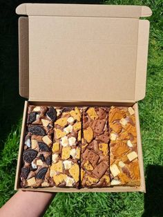 a box filled with lots of different types of cookies and crackers on top of green grass