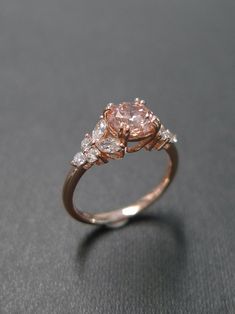 an engagement ring with three stones on top and one stone in the middle, sitting on a black surface