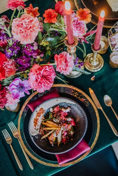 a plate with food on it next to some candles and pink flowers in the background