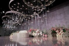 a white wedding cake sitting on top of a table next to flowers and chandelier