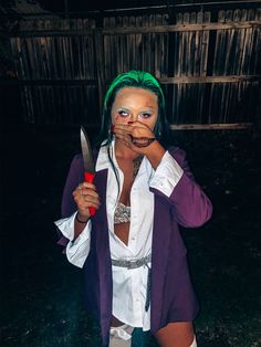 a woman with green hair and makeup holding a knife