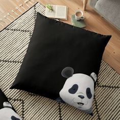 a black and white panda bear floor pillow sitting on top of a rug next to a chair