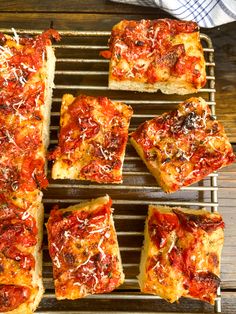 several square slices of pizza sitting on top of a cooling rack