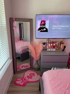 a bedroom with pink bedding, mirror and television