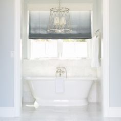 a white bath tub sitting under a window in a bathroom