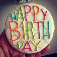 a happy birthday decorated cookie in someone's hand