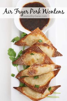 air fryer pork wontons on a white plate with sauce and parsley