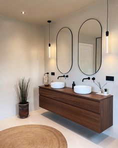 a bathroom with two sinks and mirrors on the wall next to a potted plant