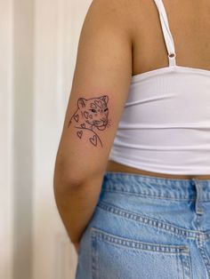 a woman with a cat tattoo on her left arm and shoulder, standing in front of a white wall