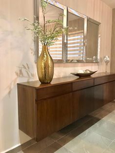 a vase filled with flowers sitting on top of a wooden table next to a mirror