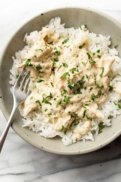 a bowl filled with rice covered in chicken and garnished with parsley on top