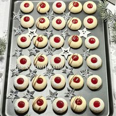 cookies decorated with red and white icing are on a baking sheet, ready to be baked