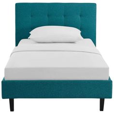 a bed with a blue headboard and white pillows on top of it, against a white background