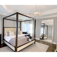 a bedroom with a four poster bed, chandelier and mirror on the wall