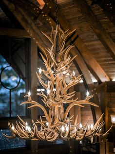 a deer antler chandelier hanging from the ceiling in a room with wood beams