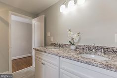 a bathroom with marble counter tops and white cabinets