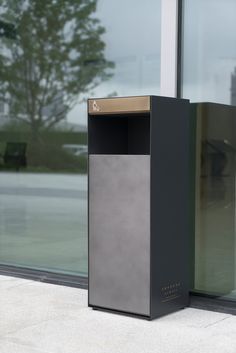 a metal trash can sitting next to a large window on the side of a building