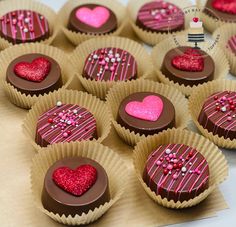 there are many heart shaped chocolates in the paper cupcake wrappers on the table