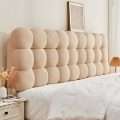 an upholstered headboard on a bed in a bedroom with white sheets and pillows