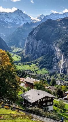 the mountains are covered in snow and green grass, with houses on either side of them