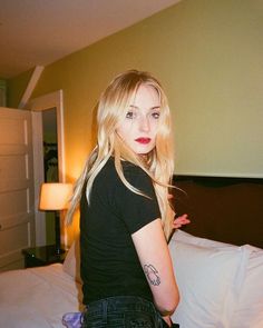 a woman standing on top of a bed next to a lamp