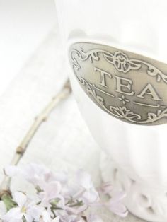 there is a tea cup with the word tea on it and flowers in the background