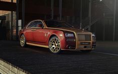 a red and gold rolls royce parked in front of a building