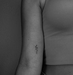 a black and white photo of a woman's arm with a small flower tattoo on it