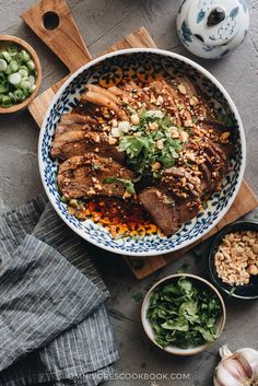 a bowl filled with meat and vegetables on top of a wooden cutting board next to other bowls