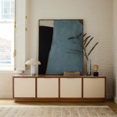 a living room with a large painting on the wall next to a table and lamp