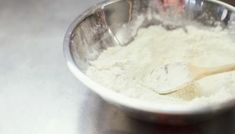 a metal bowl filled with flour and a wooden spoon