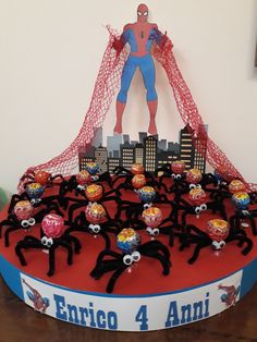 a cake with spiderman on it and other decorations in the shape of people holding hands