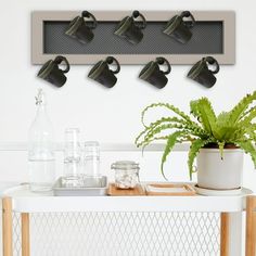 a white table topped with a potted plant next to a wall mounted light fixture