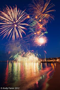 fireworks are lit up in the night sky over water