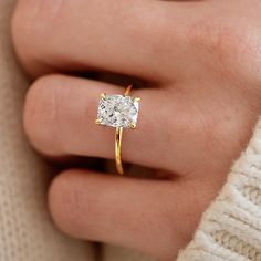 a woman's hand wearing a yellow gold ring with a diamond