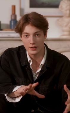 a young man sitting on top of a couch holding his hands out to the side