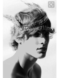 a black and white photo of a young man wearing a headband with feathers on it