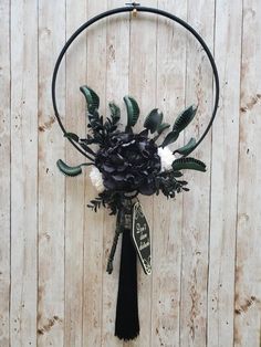 a black and white flower arrangement hanging from a hoop on a wooden wall with the word love written in it