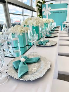 the table is set with white and aqua colored napkins, wine glasses, and silverware