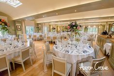 a room filled with lots of tables covered in white tablecloths and centerpieces