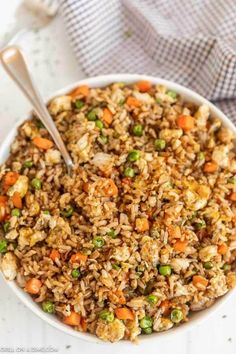 a white bowl filled with rice and carrots on top of a table next to a napkin