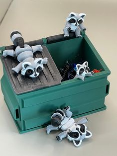 two toy raccoons are sitting in a green box