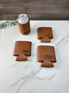 four brown leather coasters sitting on top of a white marble counter next to a can