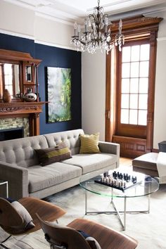 a living room filled with furniture and a chandelier hanging from the ceiling over a fire place