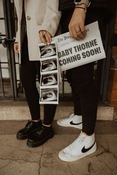 two people standing next to each other holding papers with baby thorne coming soon on them